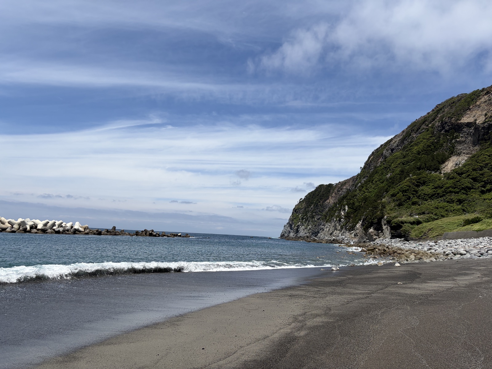 新島の黒っぽい砂浜と断崖